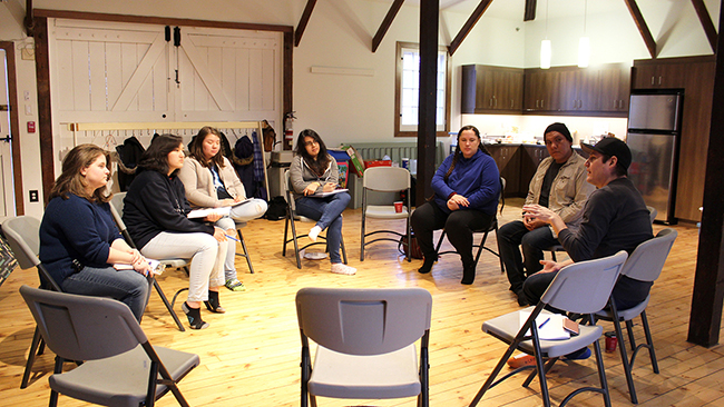 A group of Youth Cabinet members and facilitators sit in a circle with Tyler Pennock in 2017.
